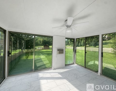 A sunny day in a spacious room with a ceiling fan and sliding glass doors.