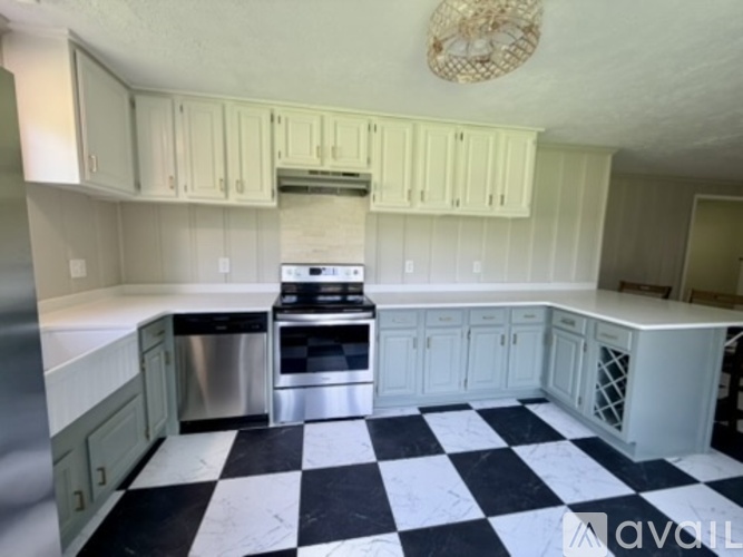 A kitchen with white cabinets and a black and white checkered floor.