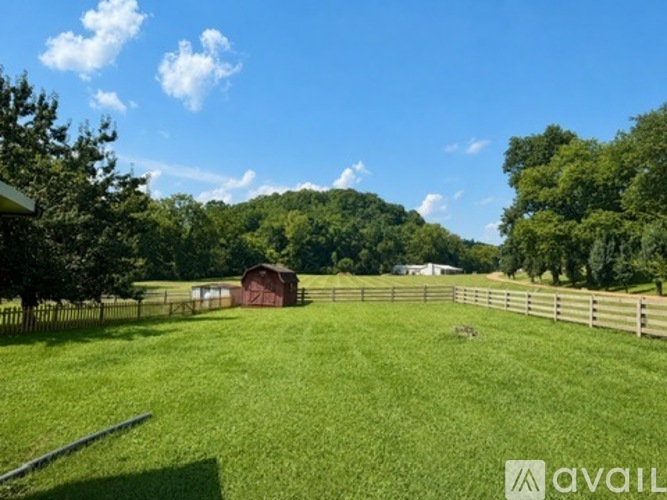 A grassy field with a fence and a barn in the distance.