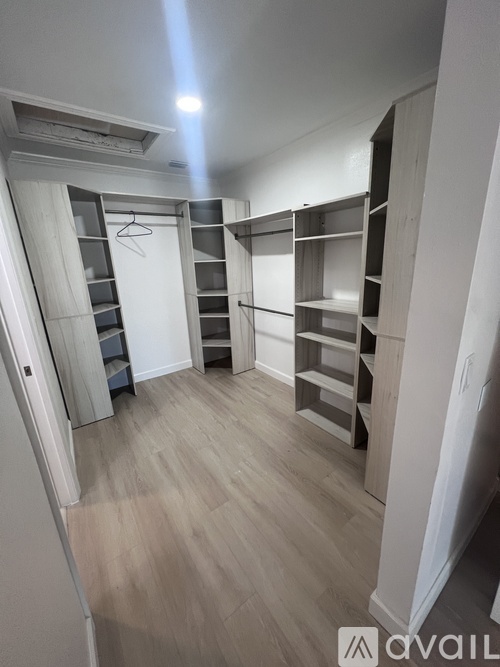 A spacious walk-in closet with wooden shelves and a hanging rod.