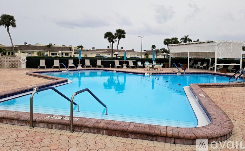 A large outdoor swimming pool with a brick border and metal handrails.