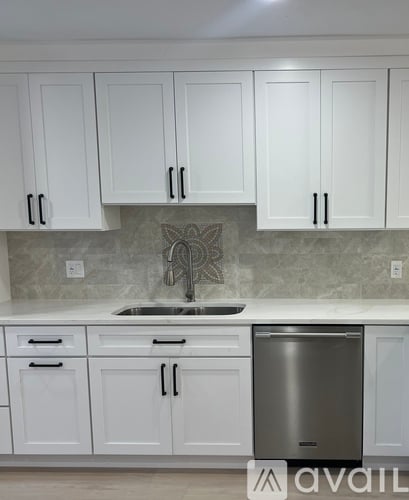A kitchen with white cabinets and a stainless steel dishwasher.