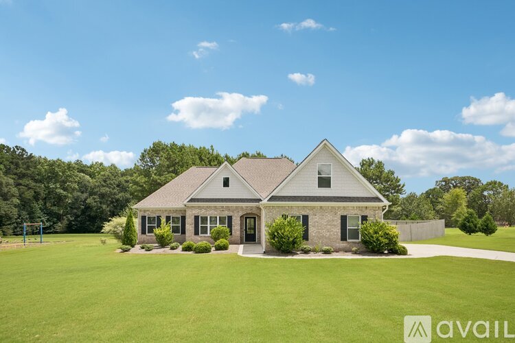 A house with a large lawn and trees in the background.
