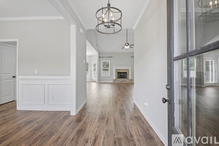 A spacious room with wood flooring and a chandelier hanging from the ceiling.