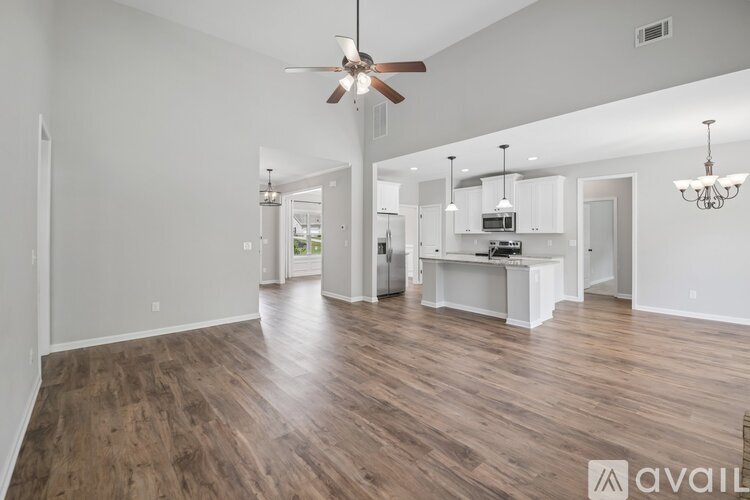 A spacious living room with wood flooring and a ceiling fan.