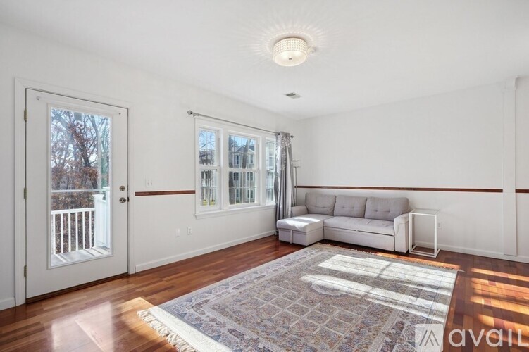A living room with a white couch and a rug on the floor.