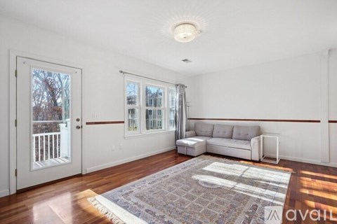 A living room with a white couch and a rug on the floor.