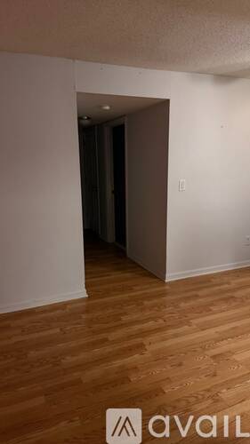 A room with wooden flooring and a doorway leading to another room.
