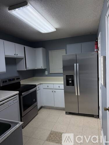 A kitchen with white cabinets and a stainless steel refrigerator.