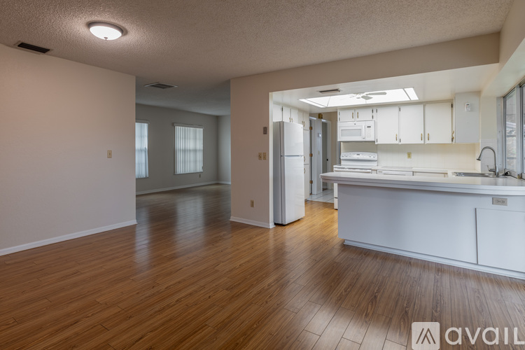 A kitchen with white cabinets and a wooden floor.