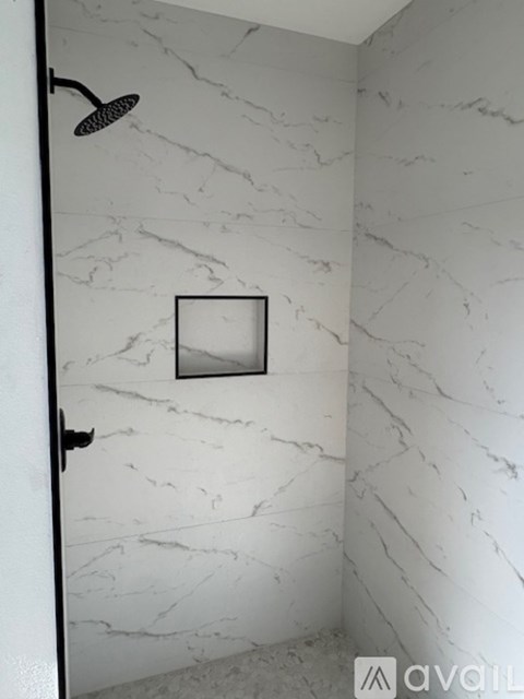 A white bathroom with a marble wall and a small mirror.