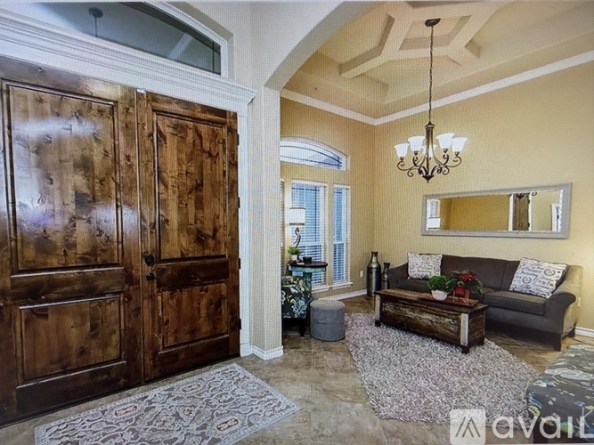 A living room with a large wooden door and a grey couch.