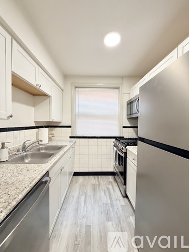 A kitchen with white cabinets and a stainless steel refrigerator.