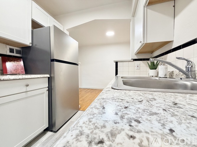 A kitchen with a black fridge and a marble countertop.