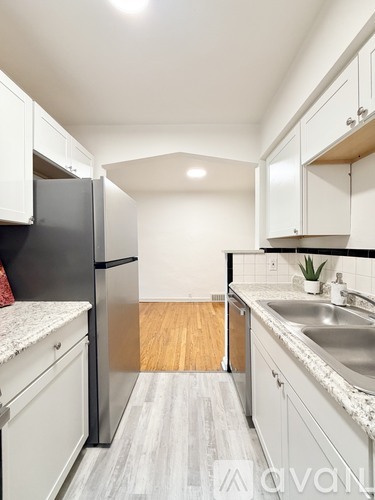 A kitchen with white cabinets and a black refrigerator.