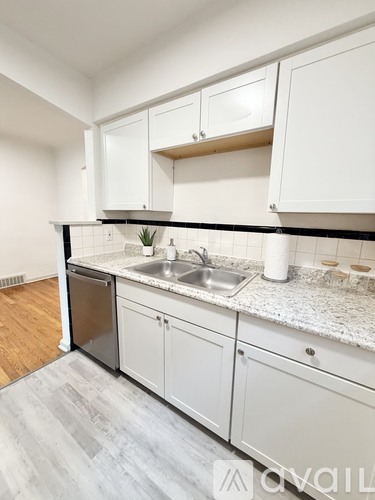 A kitchen with white cabinets and a marble countertop.