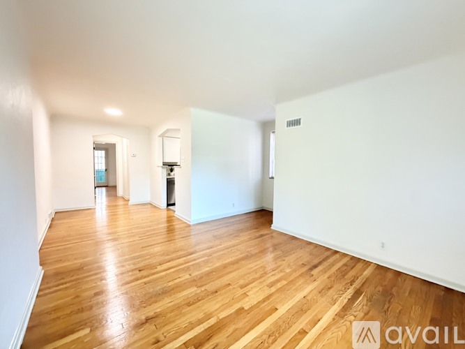 A spacious room with wooden flooring and white walls.
