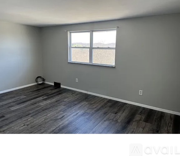 A room with a window and a wooden floor.