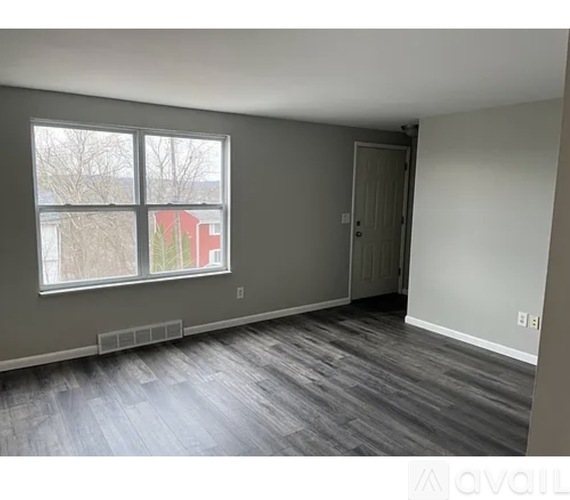 A room with a grey wall and a grey floor with a window.