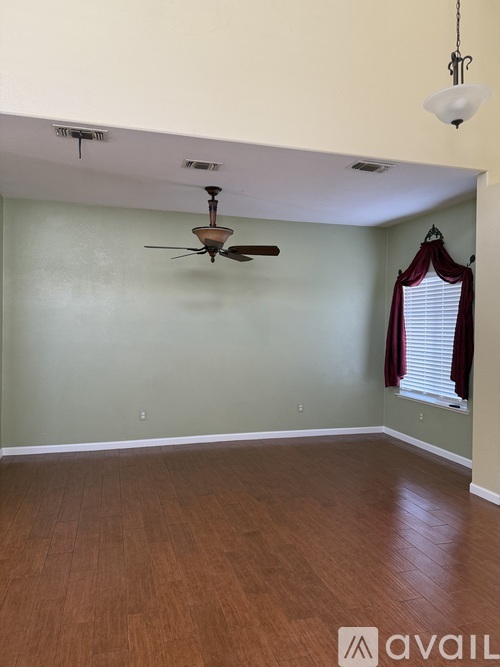 A room with a ceiling fan and wooden flooring.