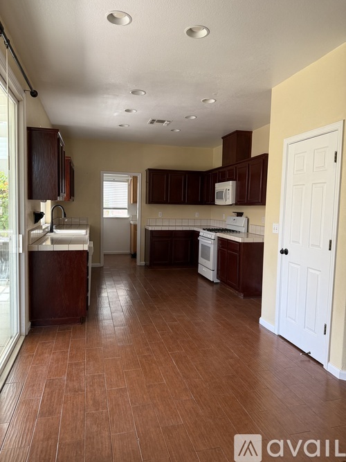 A kitchen with brown tile flooring and white appliances.