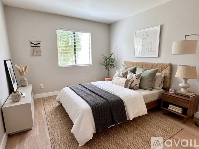 A bedroom with a large bed and a window with blinds.