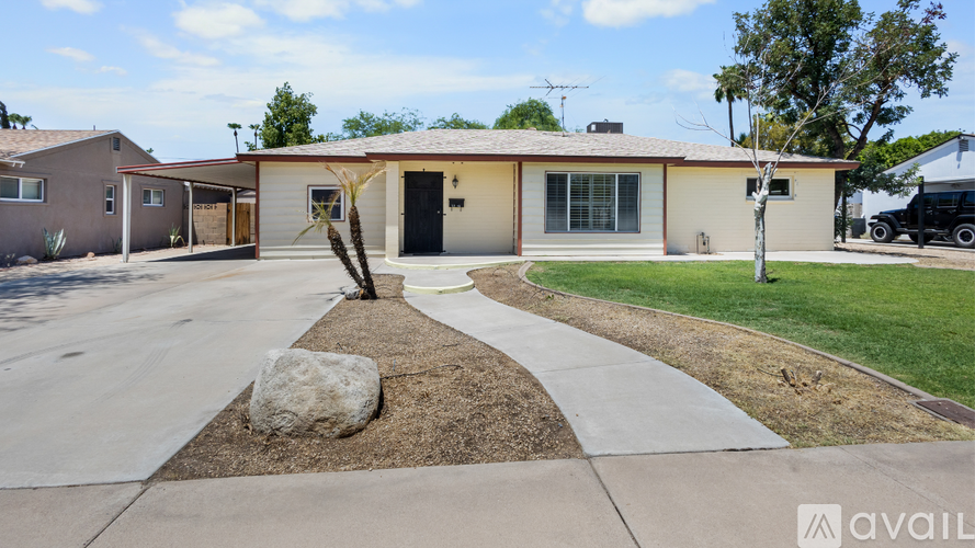 A house with a driveway and a large rock in the middle of it.