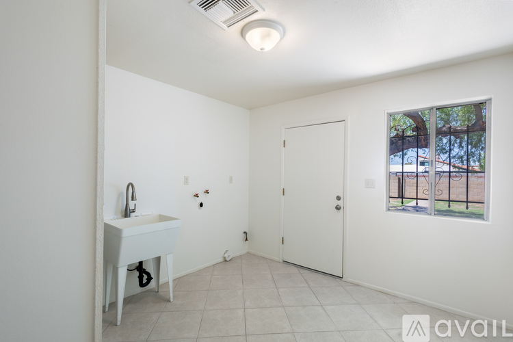 A bathroom with a white sink and a window showing a fence and trees outside.