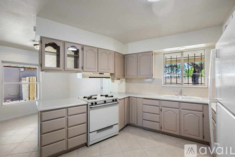 A kitchen with a white stove top oven and beige cabinets.