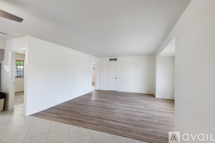 A spacious room with wooden flooring and white walls.