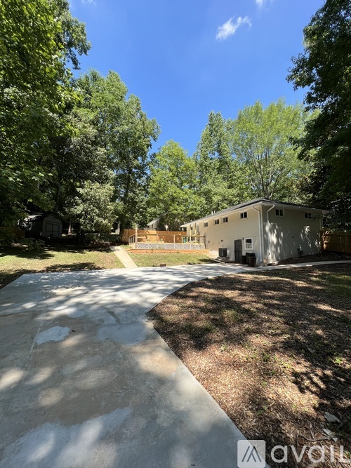 A house is surrounded by trees and has a driveway in front.