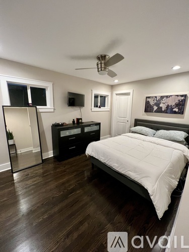 A bedroom with a bed, dresser, mirror, and ceiling fan.