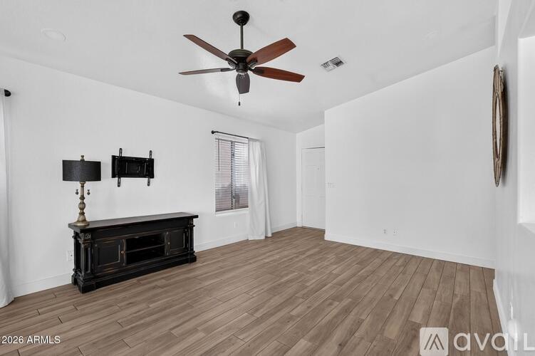 A spacious room with a ceiling fan and a wooden floor.