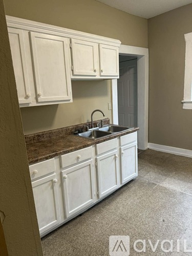 A kitchen with white cabinets and a brown countertop.
