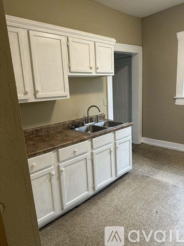 A kitchen with white cabinets and a brown countertop.