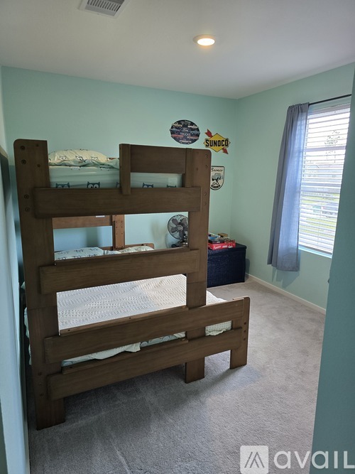 A wooden bunk bed with a white mattress is in a room with a blue wall.