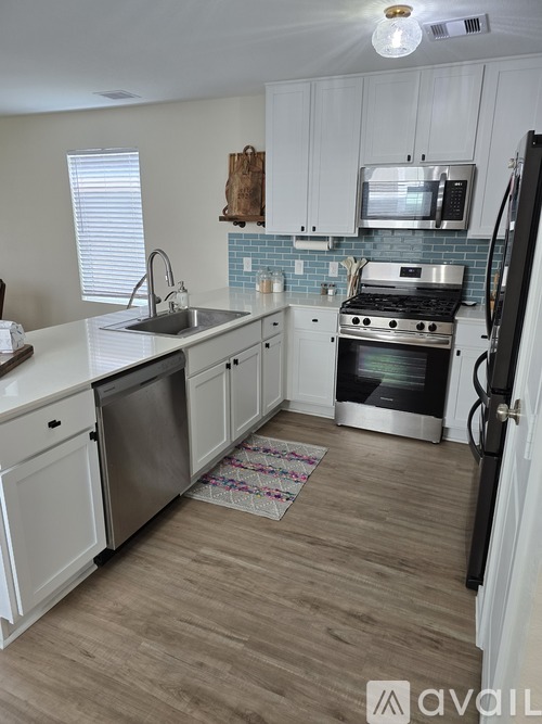 A kitchen with white cabinets and a wooden floor.