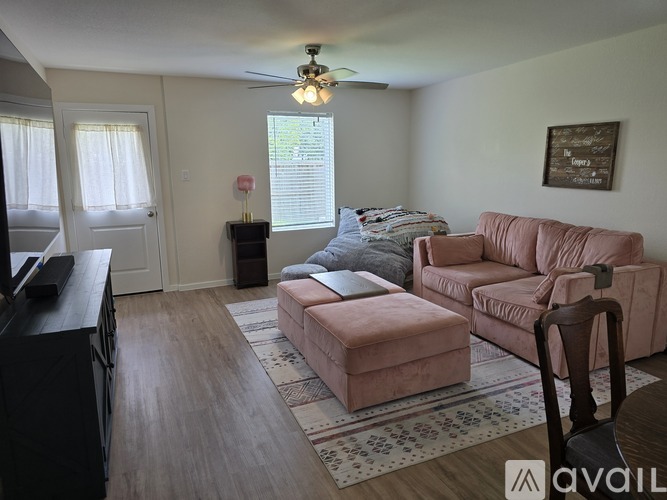 A living room with a pink couch and a brown ottoman.