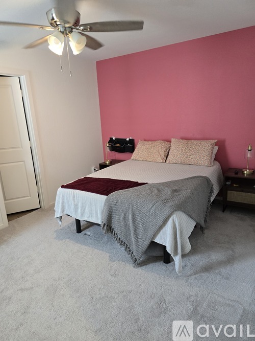A bedroom with a bed, pillows, and a ceiling fan.