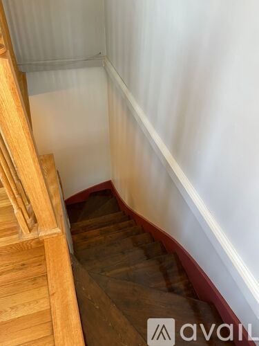 A wooden staircase with a white wall on the side.