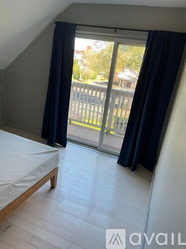 A bedroom with a bed, wooden frame, and a sliding glass door leading to a balcony.