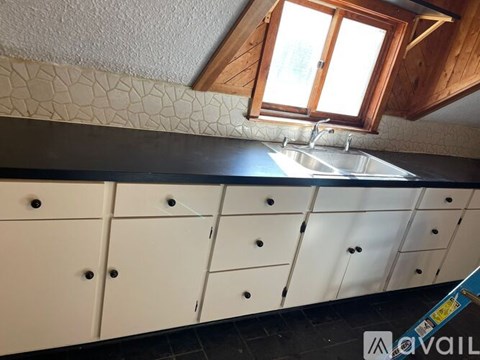 A kitchen with white cabinets and a window above the sink.