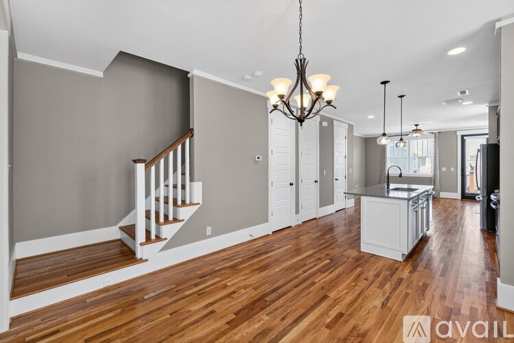 A spacious room with wooden floors and a staircase.