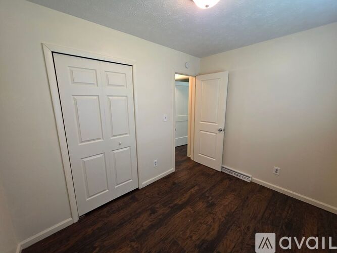 A room with a white door and a wooden floor.
