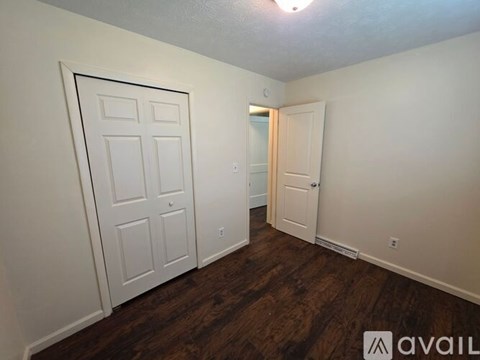 A room with a white door and a wooden floor.