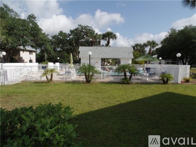 A white fence encloses a green lawn with a building in the background.