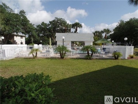 A white fence encloses a green lawn with a building in the background.
