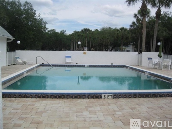 A pool surrounded by a white wall and a brick floor.