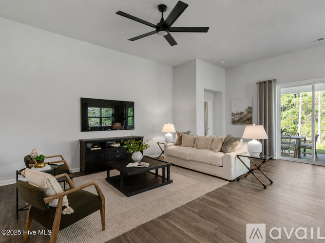A living room with a black ceiling fan, a television, a couch, and a chair.