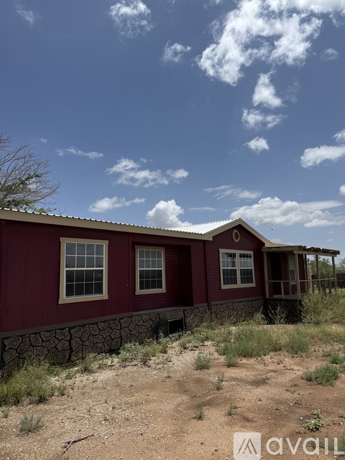 A red house with a stone wall in front.